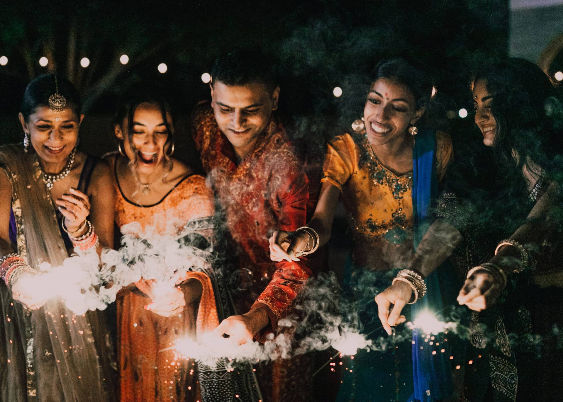 Festive Diwali scene with friends in traditional outfits lighting sparklers and enjoying the celebration.