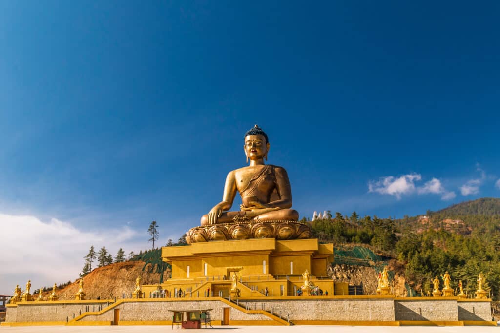 Giant Buddha Statue in Thimphu, Bhutan shown against a bright blue, clear sky